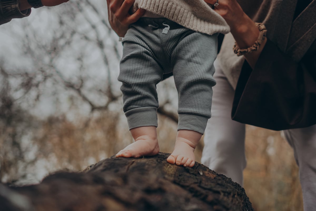 a baby is standing on a log in the woods