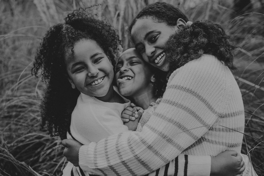 black and white photo of three sisters hugging in a field